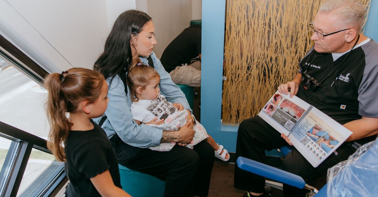 mom and two kids learning about myofunctional therapy from dentist